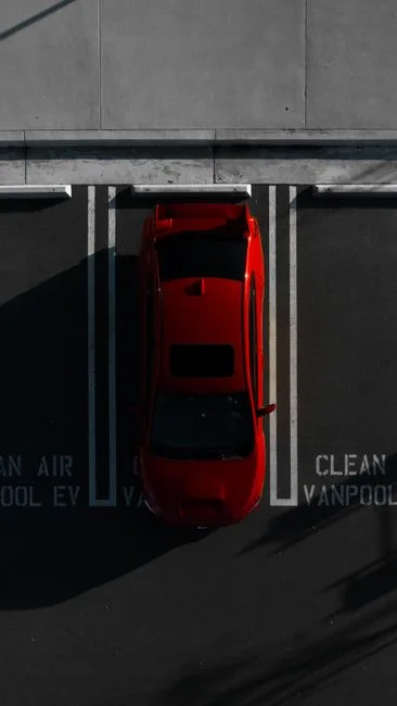 Aerial shot of a red car parked in an urban lot designated for clean air vehicles.