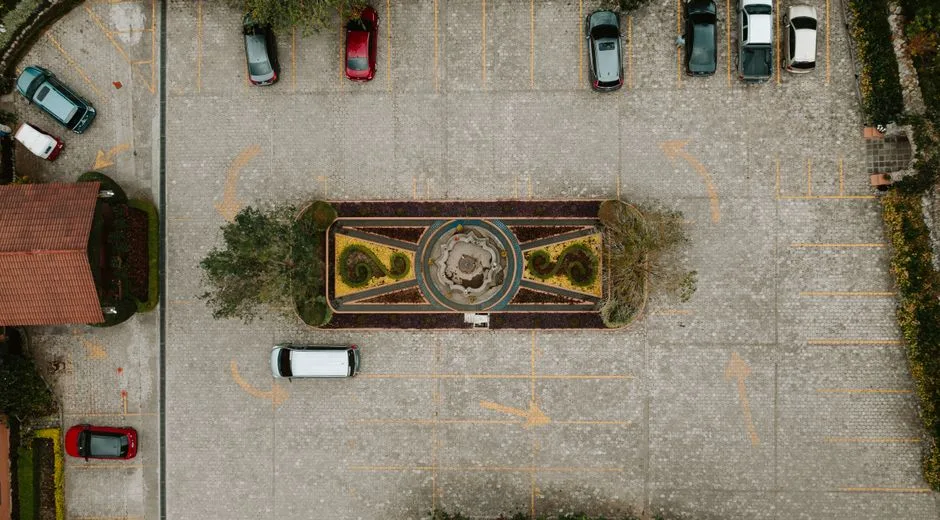 Aerial shot of parking lot with decorative central fountain and parked cars.