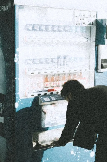 A man interacts with a vending machine in a modern city environment.