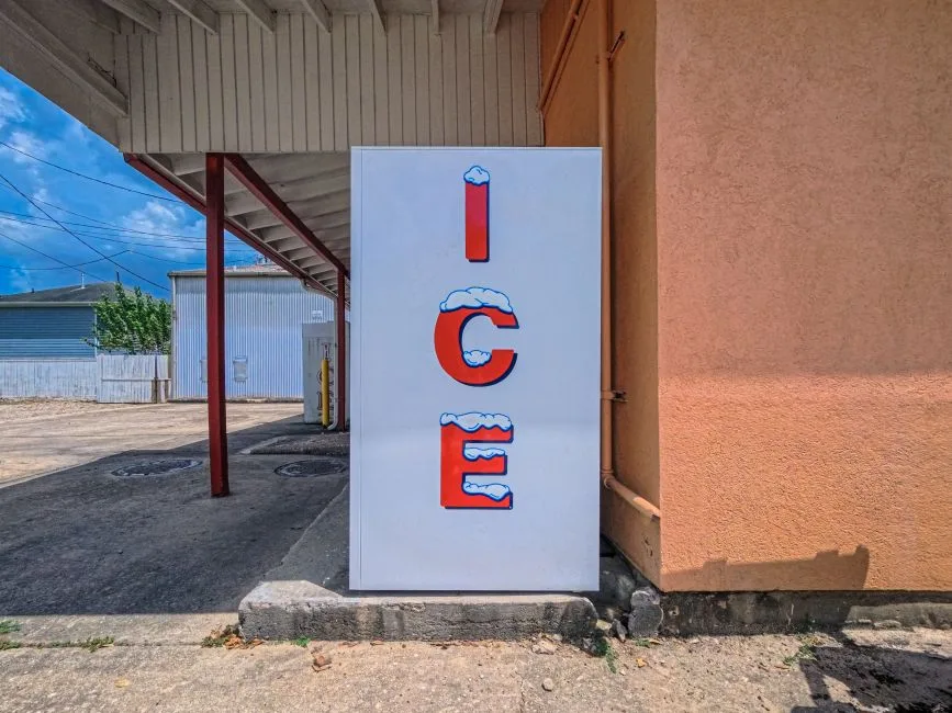 Outdoor ice machine with bright signage in Houston, TX on a sunny day.
