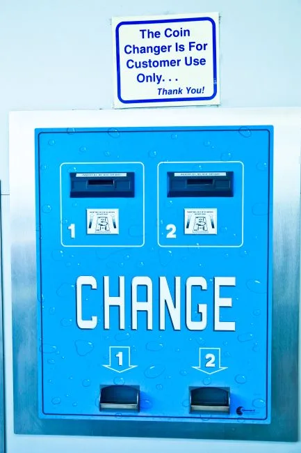 Close-up of a blue coin changer machine with instructions, ideal for customer self-service imagery.