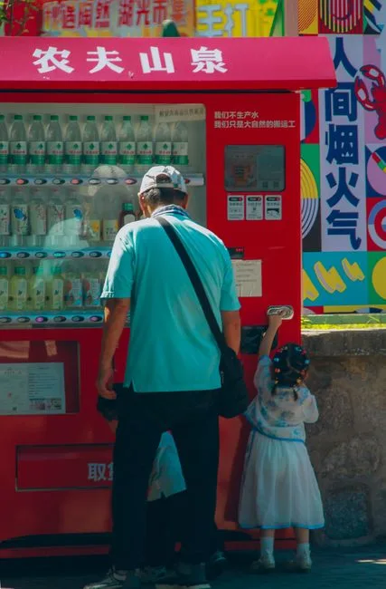 A father and daughter using a vending machine on a colorful street. Bright and lively atmosphere.