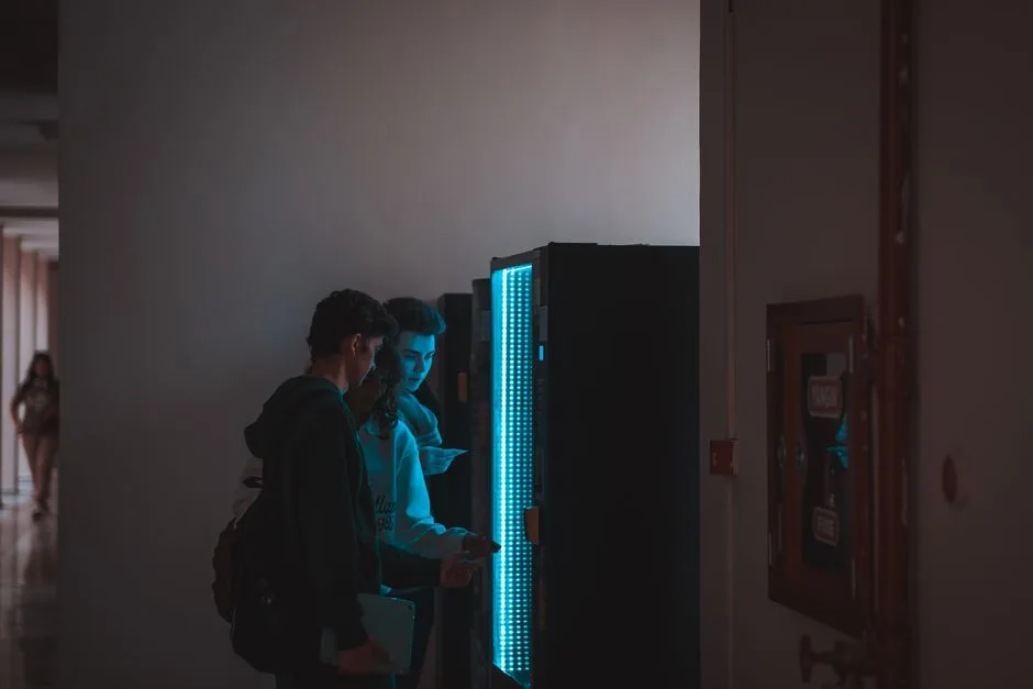 Group of teenagers using a vending machine in a school corridor, captured in ambient lighting.