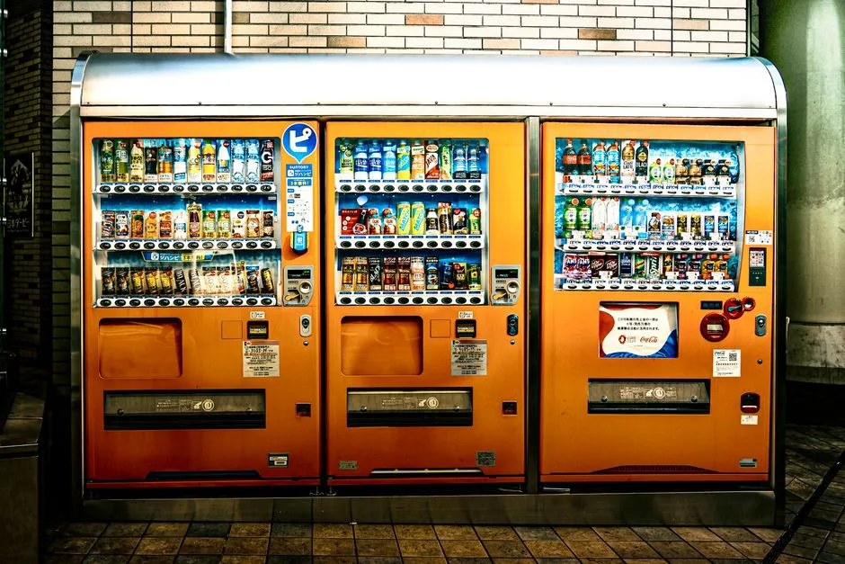 Eye-catching orange vending machines offer a variety of drinks indoors, illuminated brightly.
