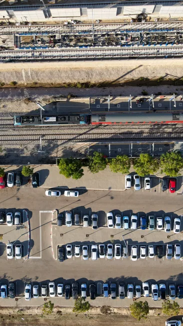 Aerial shot of a train station and parking lot in Petah Tikva, Israel, showcasing urban transportation and infrastructure.