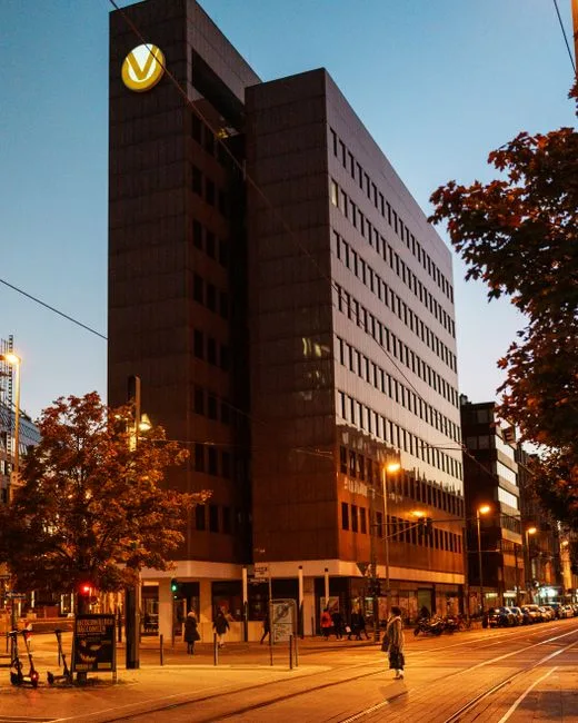 A bustling city street with modern architecture and vibrant evening lights.