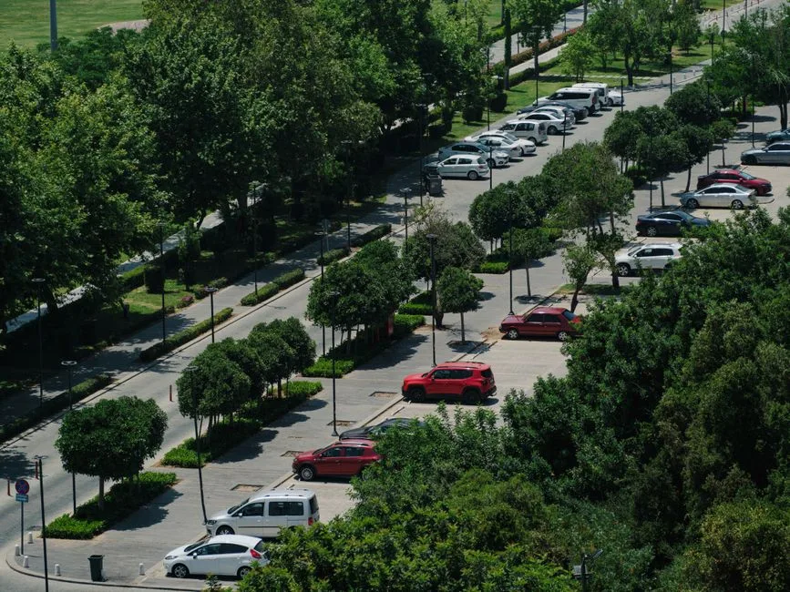 Aerial view showcasing a parking lot surrounded by lush trees and parked cars.