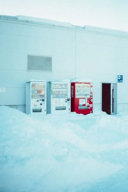 Three vending machines covered in snow outside a building in wintery Hokkaido, Japan.